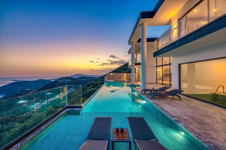 A modern house with an infinity pool looking over the water at dusk